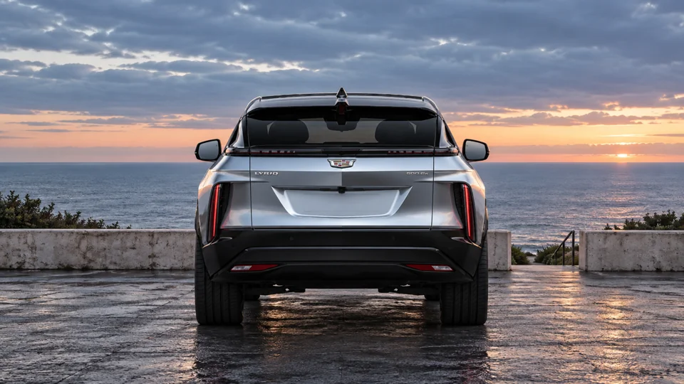 Silver Cadillac rear view overlooking the coast at sunset